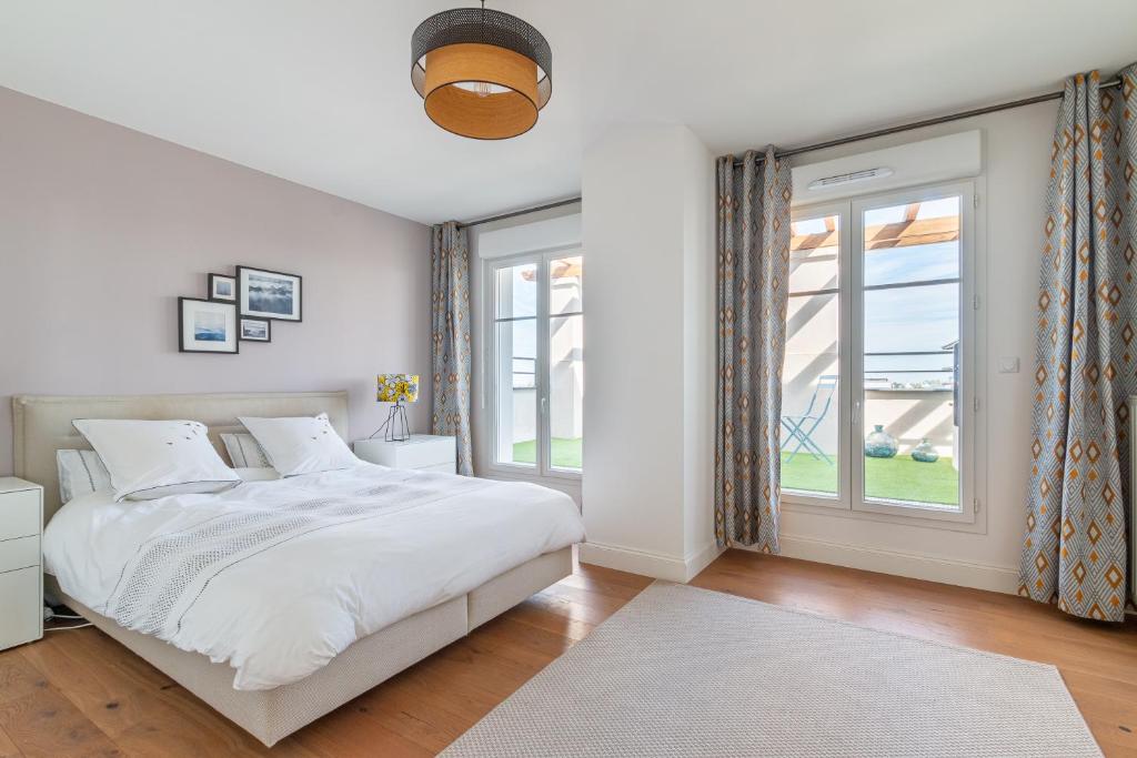 een witte slaapkamer met een bed en een raam bij PENTHOUSE Luxe DISNEYLAND PARIS in Chessy