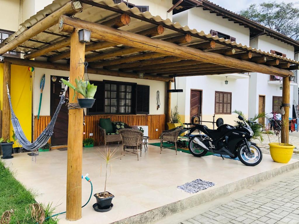 een patio met een motorfiets geparkeerd onder een houten pergola bij Casa riviera in Paraty