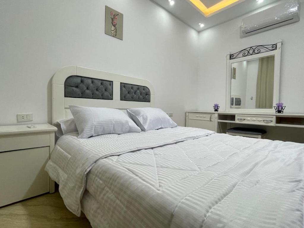 Sweet Couple Home في الغردقة: غرفة نوم بيضاء مع سرير كبير ومرآة