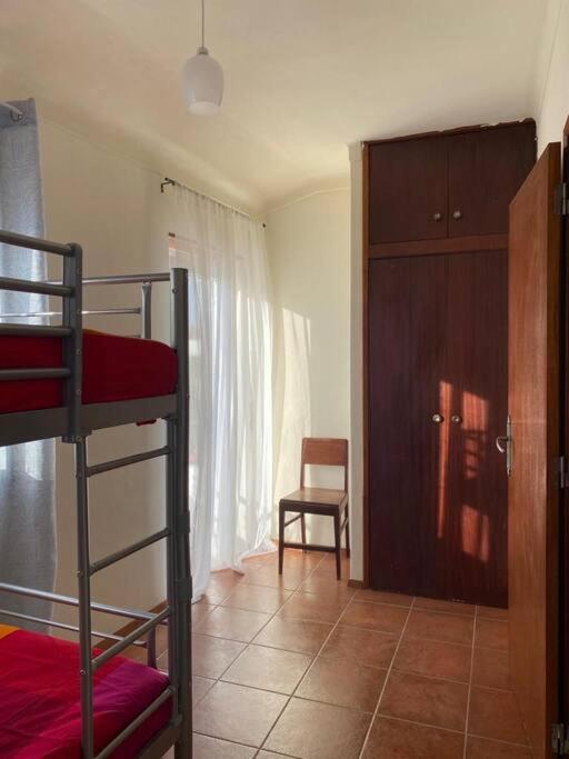 um quarto com um beliche, uma cadeira e uma porta em Caminho da Vila moradia. em Escalos de Cima