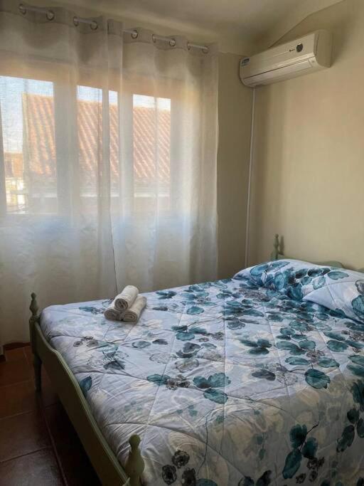 a bedroom with a bed and a window with curtains at Caminho da Vila moradia. in Escalos de Cima