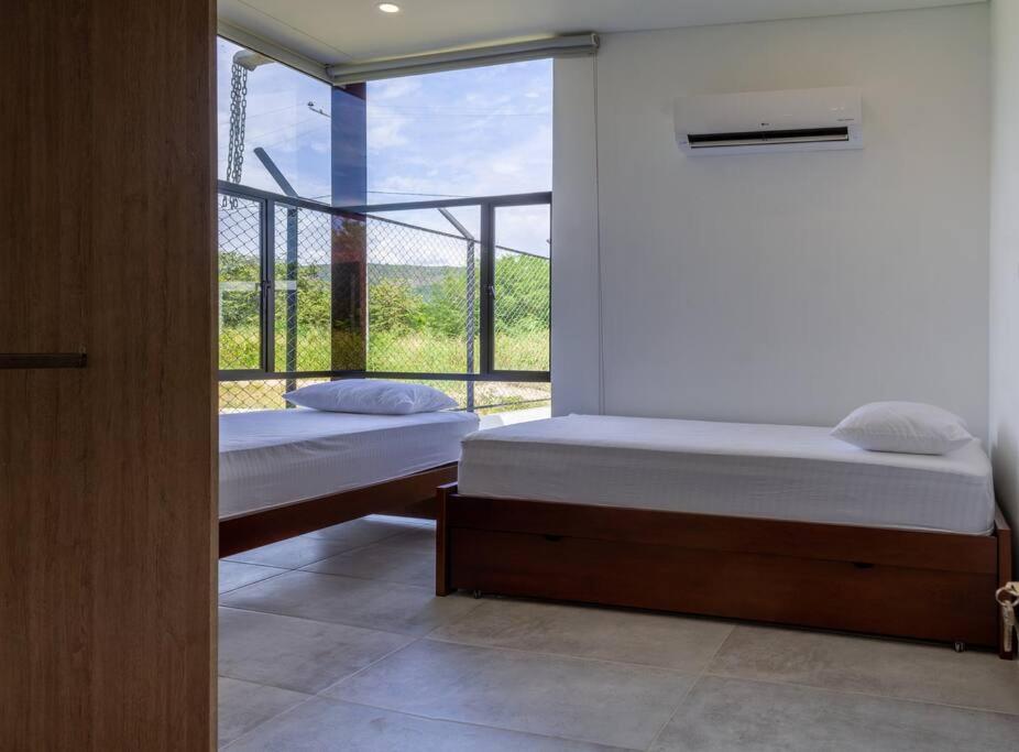 2 camas en una habitación con ventana en Casa Campestre Ensueño en Ricaurte