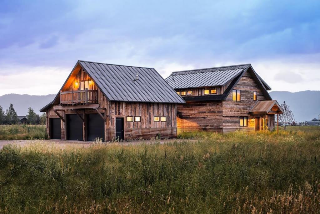 una casa de madera en un campo con montañas en el fondo en Beautiful 5 BR Wild Mustang Home in Victor, ID, en Victor