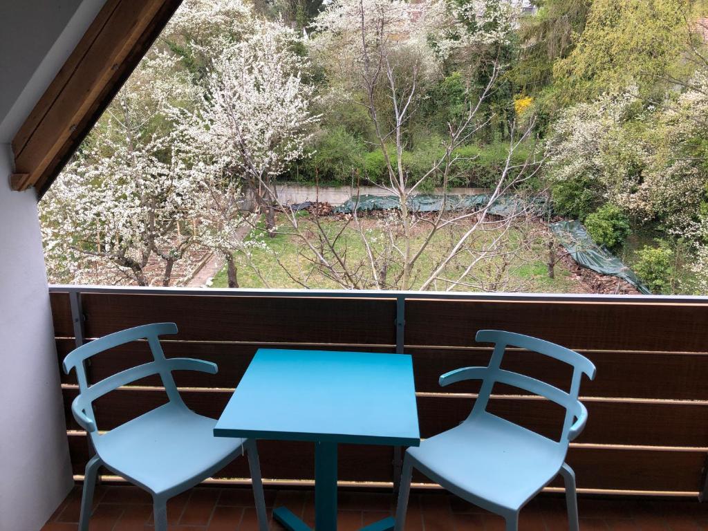 zwei blaue Tische und Stühle auf einem Balkon mit Fenster in der Unterkunft Blaues Zimmer mit grossem Balkon & Bad nur 16 km nach Würzburg! in Mainstockheim