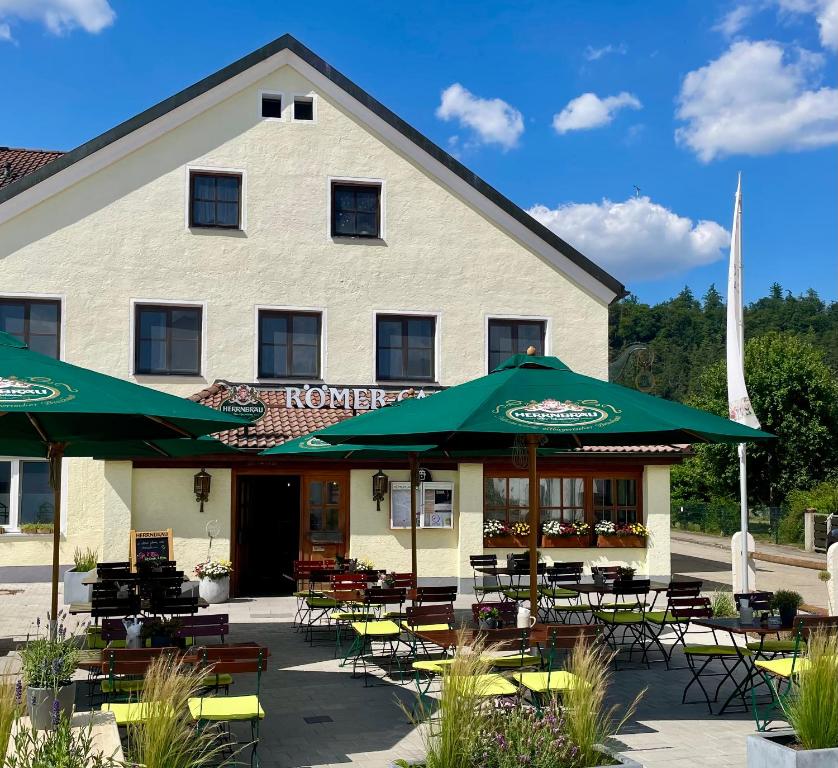 a building with tables and chairs and umbrellas at Römercastell Wirtshaus & Hotel in Böhming
