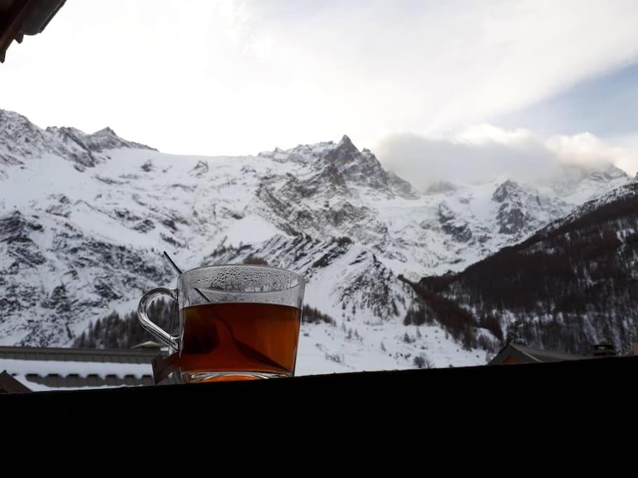 a cup of tea sitting on a table with a snow covered mountain at Le Lodge - Au coeur du village in La Grave