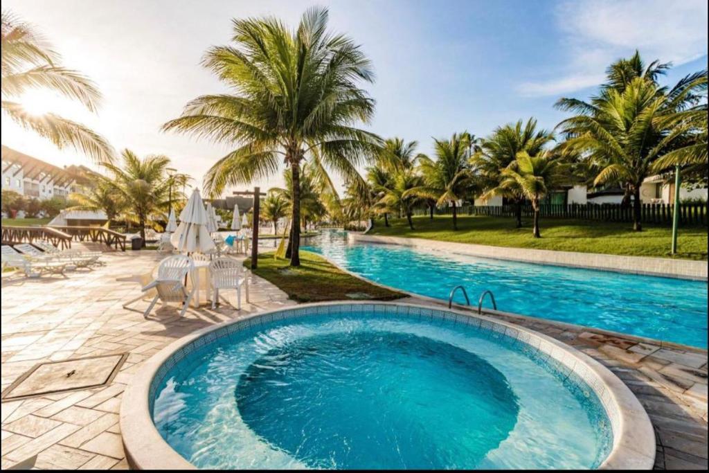 - une piscine avec des palmiers dans un complexe dans l'établissement Porto Beach Resort - Beach Class Muro Alto, à Porto de Galinhas