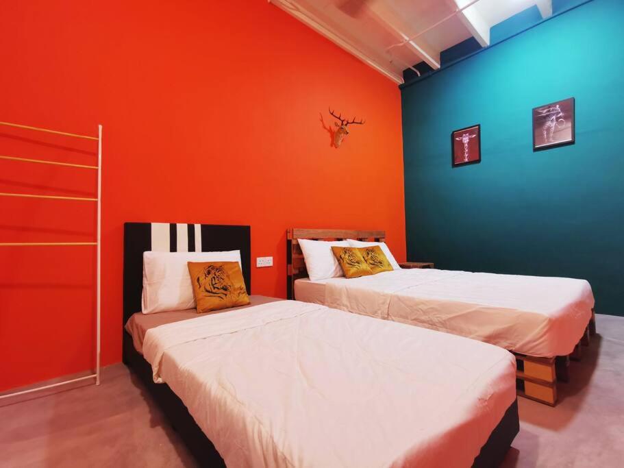 Duas camas num quarto com uma parede laranja em Ipoh town centre - safari 5 pax(2BR) em Ipoh