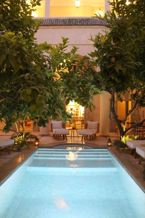 a swimming pool in a courtyard with trees and chairs at Riad Emberiza Sahari in Marrakesh