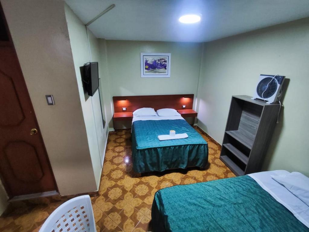 una camera d'albergo con due letti e una televisione di Hostal Continental a Nazca
