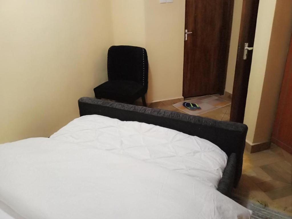 CeeJ'S Airbnb في Meru: غرفة نوم بسرير وكرسي أسود