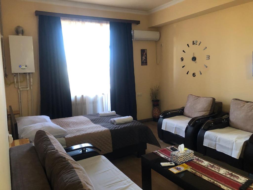 Уютная квартира в центре في يريفان: غرفة معيشة مع أريكة وساعة على الحائط