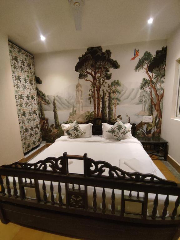 a bedroom with a bed with a painting on the wall at Kiran Apartment in Jaisalmer