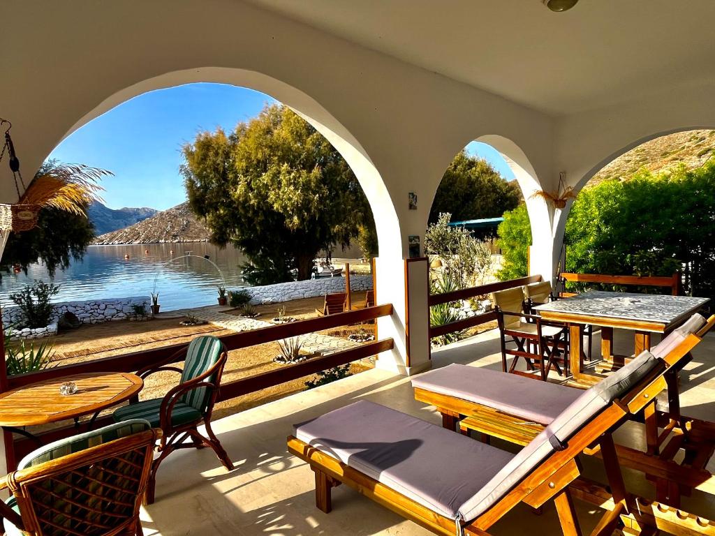 een patio met tafels en stoelen en uitzicht op het water bij Villa Evdokia in Kalymnos