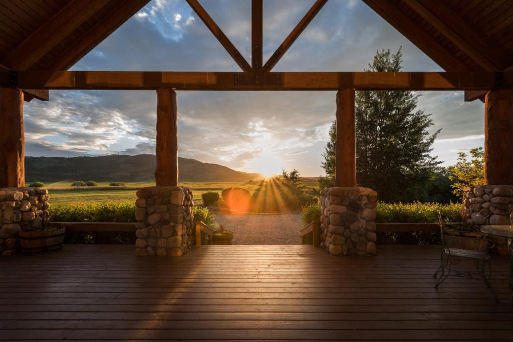 a wooden porch with a view of a sunset at Teton Riverfront Property in Victor