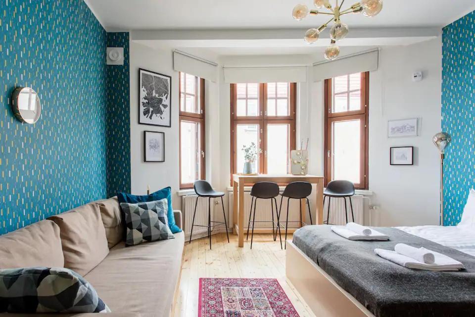uma sala de estar com um sofá e uma mesa com cadeiras em Renovated Design District Studio em Helsinque