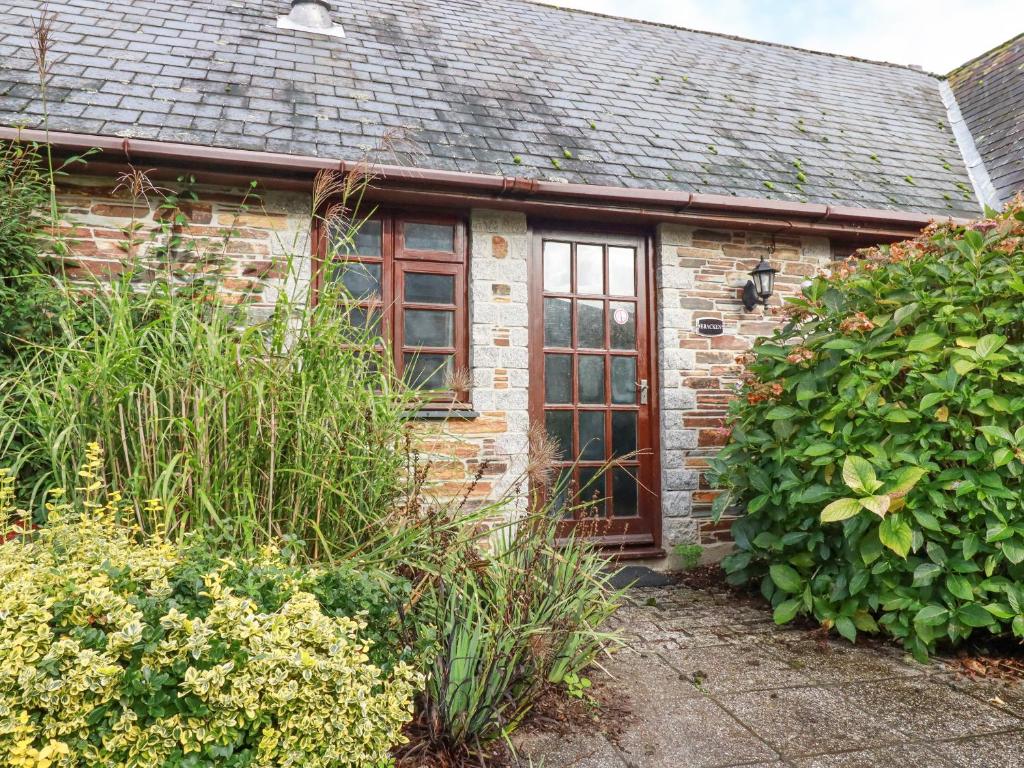 a brick house with a large window in a garden at Bracken Cottage in Bodmin
