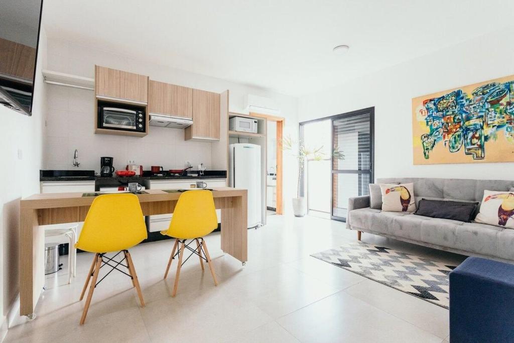 cocina y sala de estar con 2 sillas amarillas en Apartamentos modernos e aconchegantes no centro. en Poços de Caldas