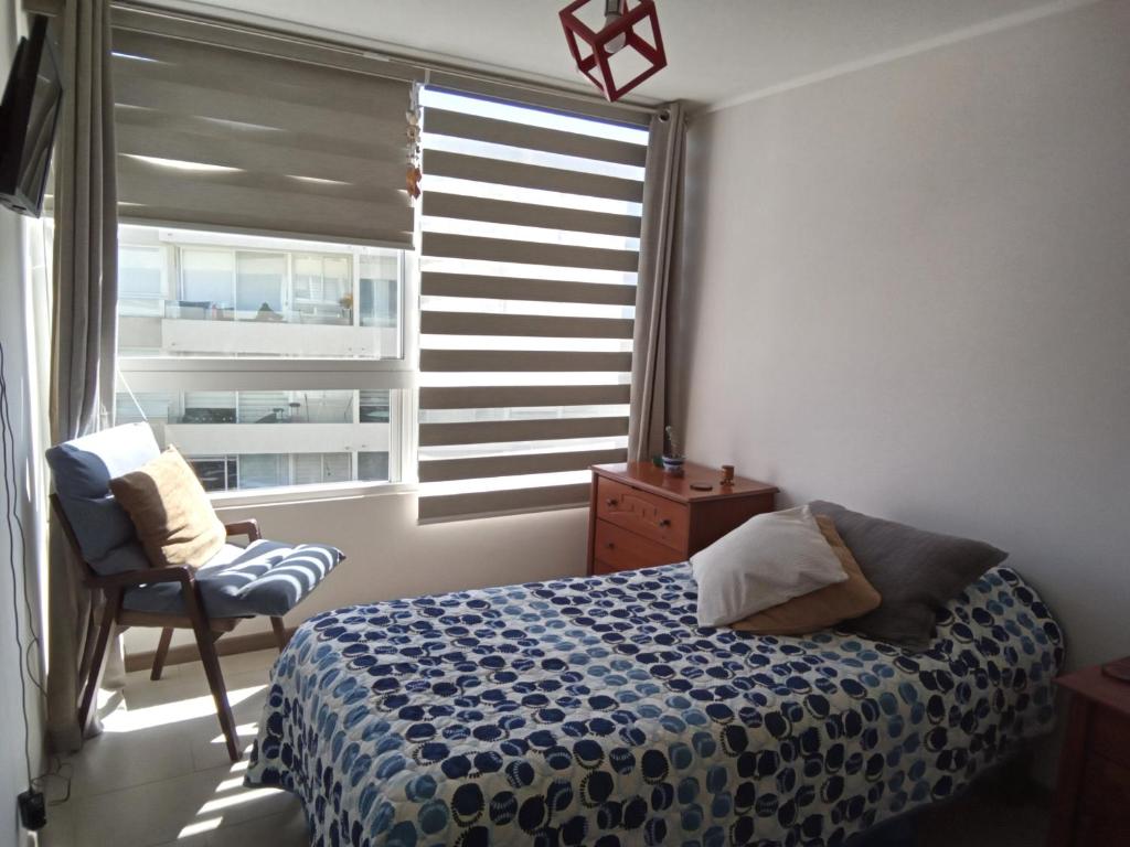 a bedroom with a bed and a chair and a window at Habitación acogedora con baño privado cerca de la Playa in La Serena