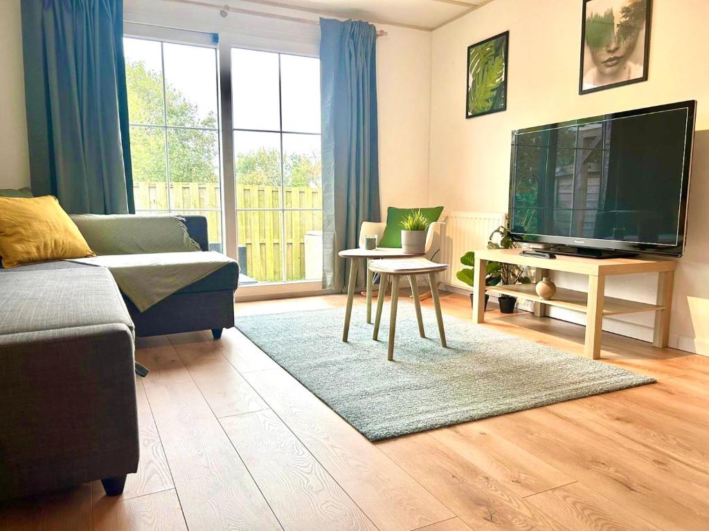 - un salon avec une grande télévision et un canapé dans l'établissement Wellness bungalow with jacuzzi &sauna&private garden near Amsterdam, à Vijfhuizen