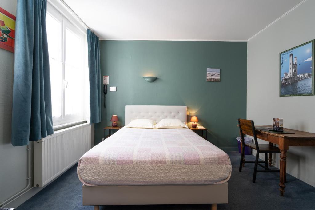 a bedroom with a bed and a desk and a window at Logis - Hôtel Le Caddy in Le Touquet-Paris-Plage