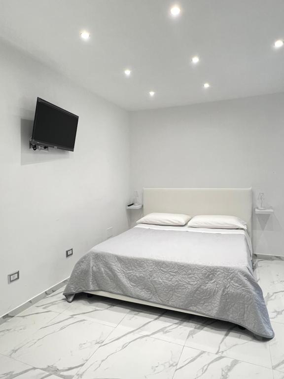 um quarto branco com uma cama e uma televisão de ecrã plano em B&B Marika Toledo em Nápoles