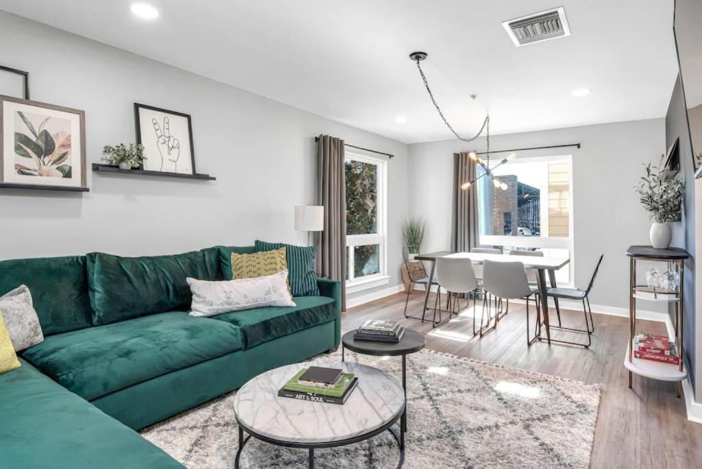 a living room with a green couch and a table at Walk to Downtown Broadway with Pool, Free Parking, and Gym in Nashville