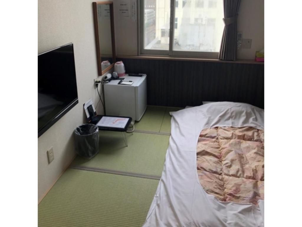 HOTEL TETORA ASAHIKAWA EKIMAE - Vacation STAY 91508v في اساهيكاو: غرفة بسرير وتلفزيون
