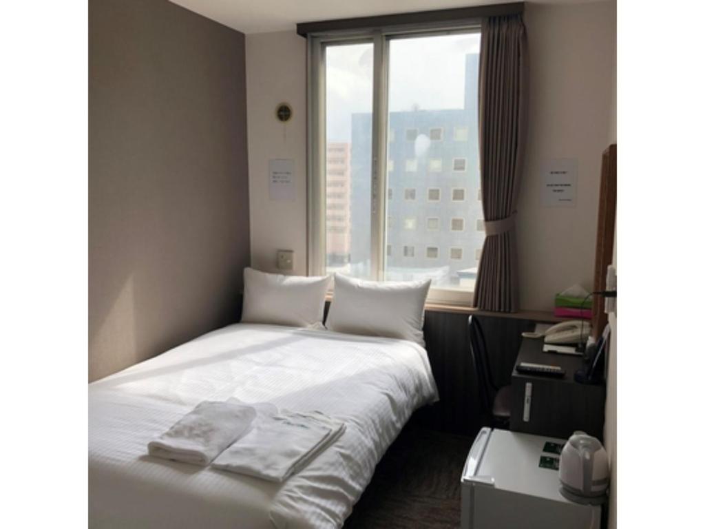 Habitación de hotel con cama y ventana en HOTEL TETORA ASAHIKAWA EKIMAE - Vacation STAY 91488v, en Asahikawa