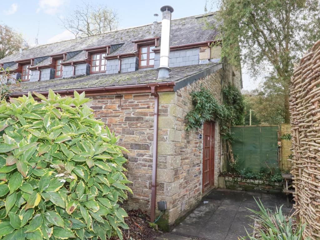 a brick house with a red door and a hedge at Minions Cottage in Bodmin