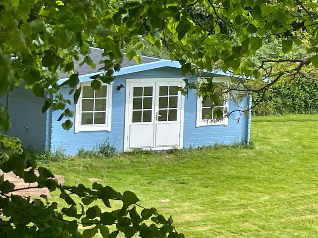 una casa azul con puertas blancas en un patio en Oak View Lodge: Cosy, Countryside Retreat, en Maybole