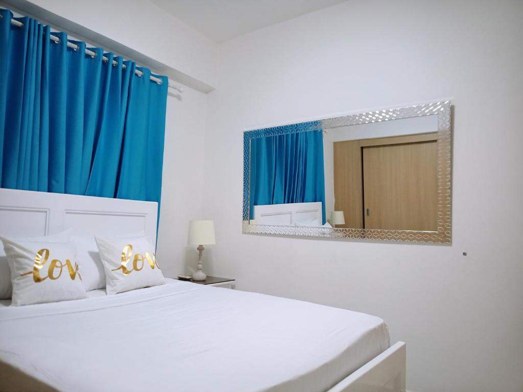 a bedroom with a bed with a mirror and blue curtains at Elegant and confortable close to Boca Chica Beach in Boca Chica