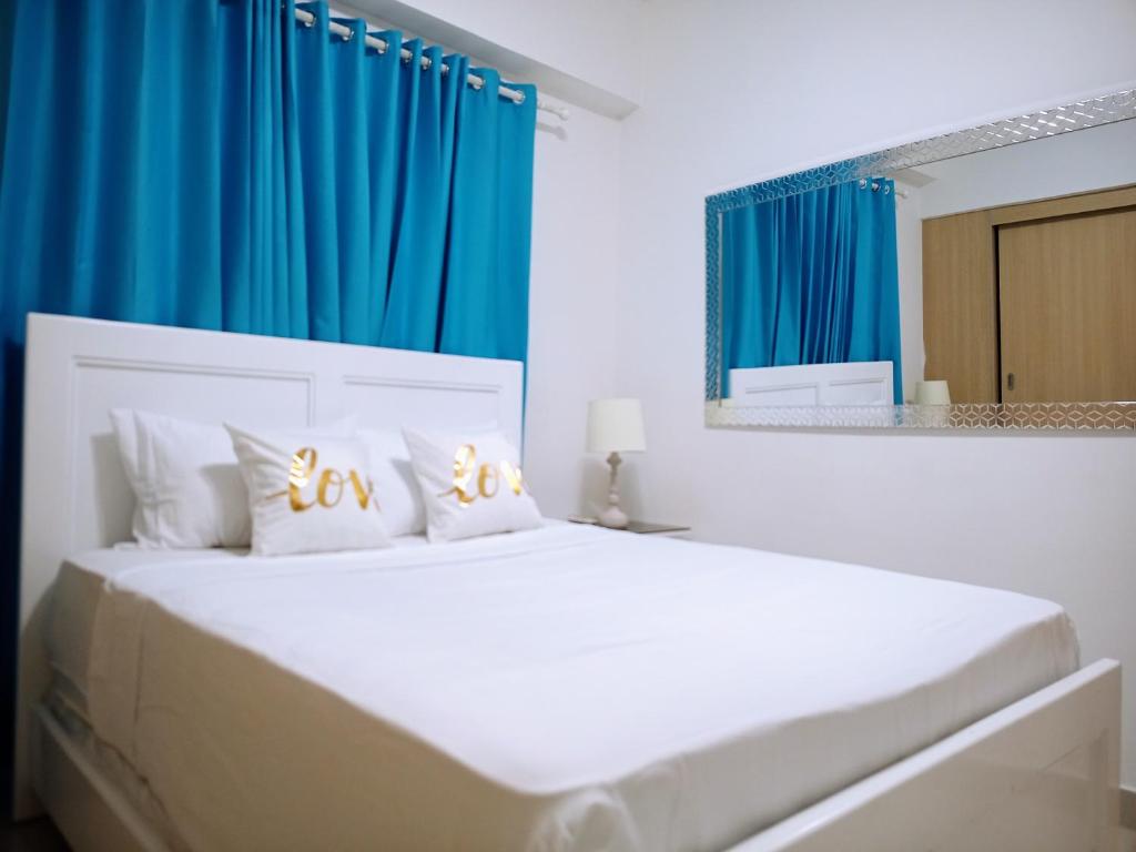 a bedroom with a large white bed with blue curtains at Confortable apto. en Boca Chica in Boca Chica