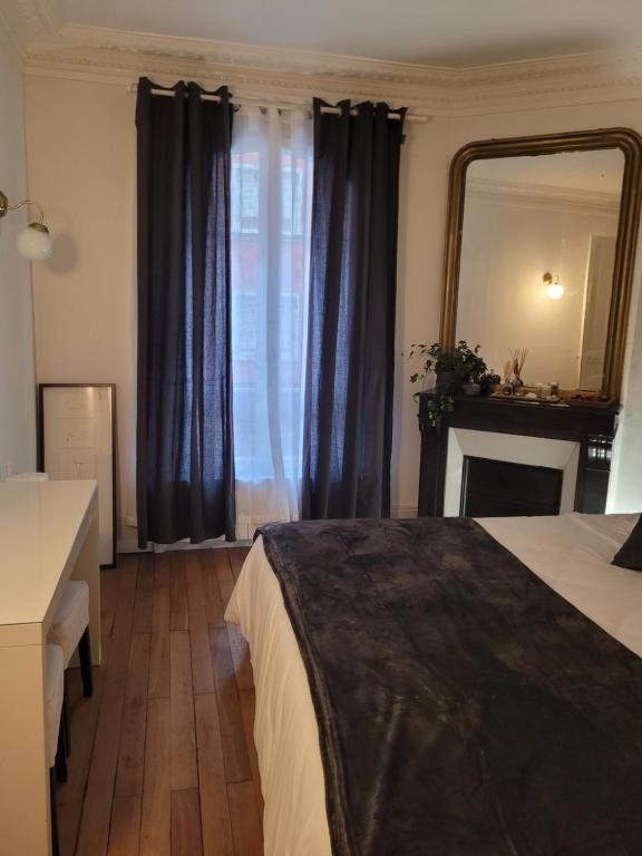 a bedroom with a bed and a mirror and a fireplace at L&#39;appartement Idéal 4 voyageurs in Boulogne-Billancourt
