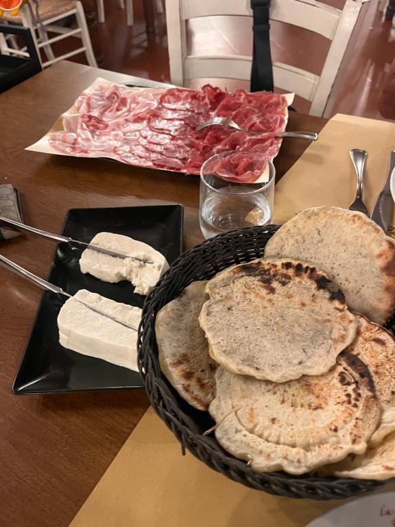 a table topped with a basket of bread and meats at Mansarda Moderna in Lunigiana con Giardino in Aulla