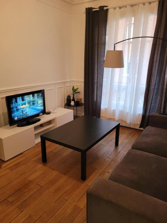 a living room with a coffee table and a television at L&#39;appartement Idéal 4 voyageurs in Boulogne-Billancourt