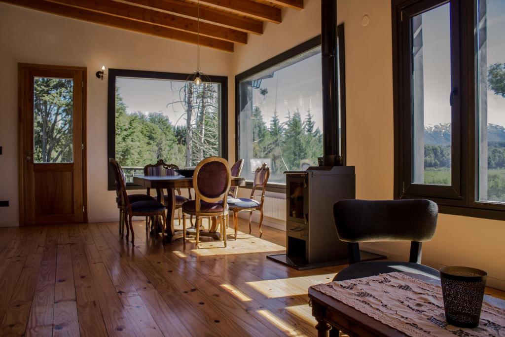 sala de estar con mesa, sillas y ventanas en BOG Casa Soñada en Villa La Angostura