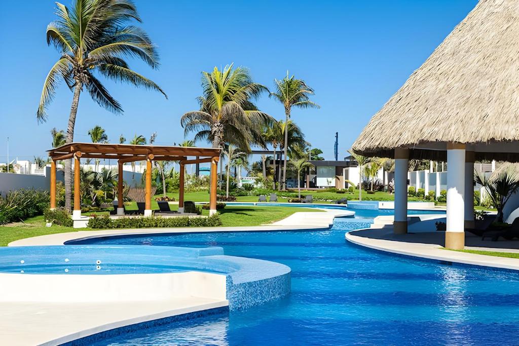 a resort pool with a gazebo and palm trees at Acapulco diamante, club de playa privado, canchas pádel para 8 huéspedes in Acapulco
