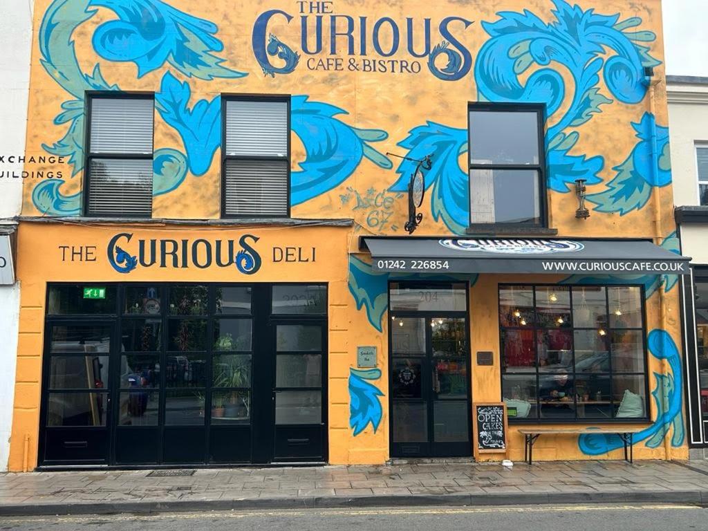 a store with a painting on the side of a building at The Curious Apartment, Cheltenham in Cheltenham