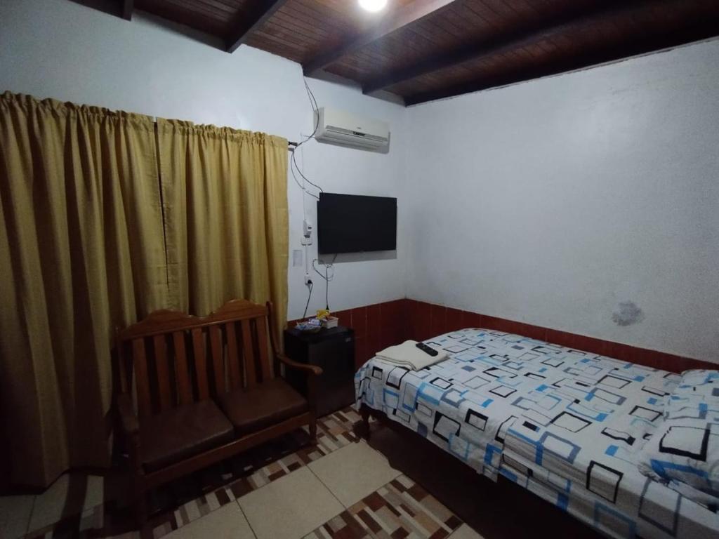 1 dormitorio con 1 cama, 1 silla y TV en LAS ORQUIDEAS Hospedaje en Pucallpa