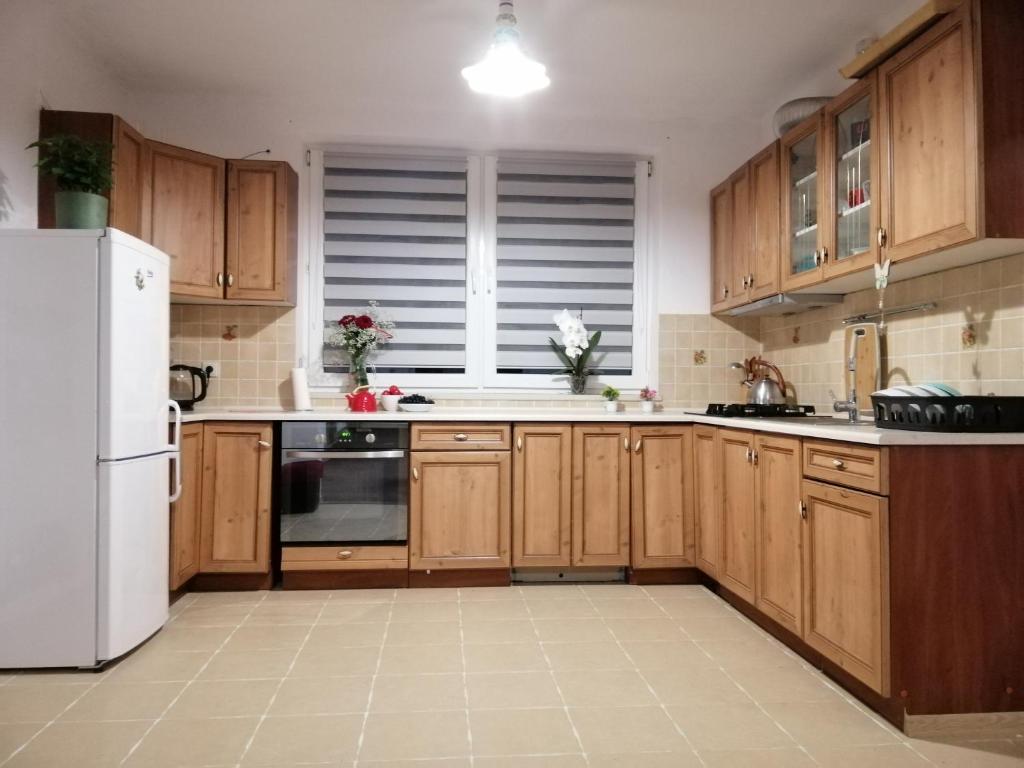 uma cozinha com armários de madeira e um frigorífico branco em Ewa Dom em Varósvia