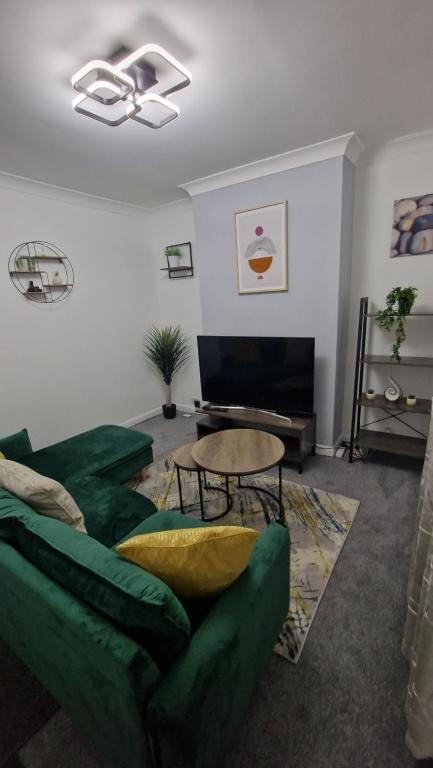 a living room with a green couch and a table at Saxon Street House in Gillingham