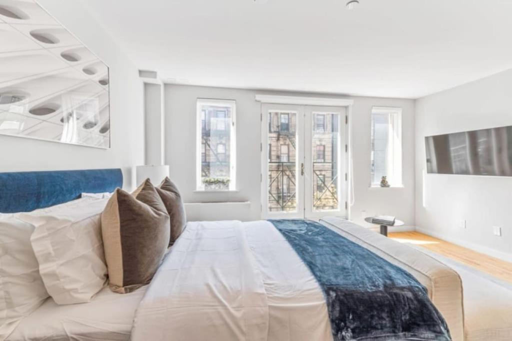 um quarto branco com uma cama grande e janelas em Luxe Studio with Charming Juliet Balcony em Nova York