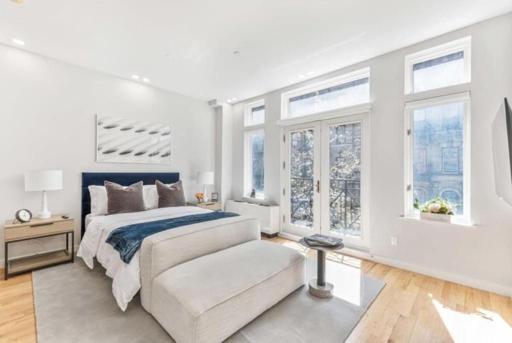 a white bedroom with a bed and a couch at Studio w Charming Juliet Balcony in Upper East in New York