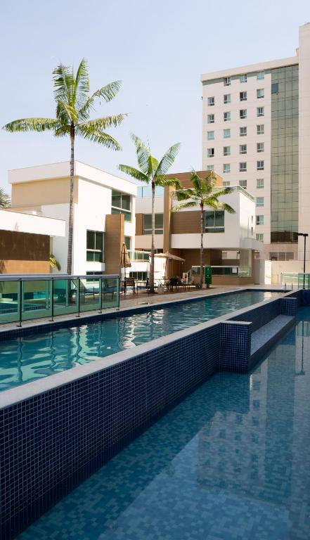 a swimming pool in front of a building with palm trees at Jade Hotel Brasília in Brasilia