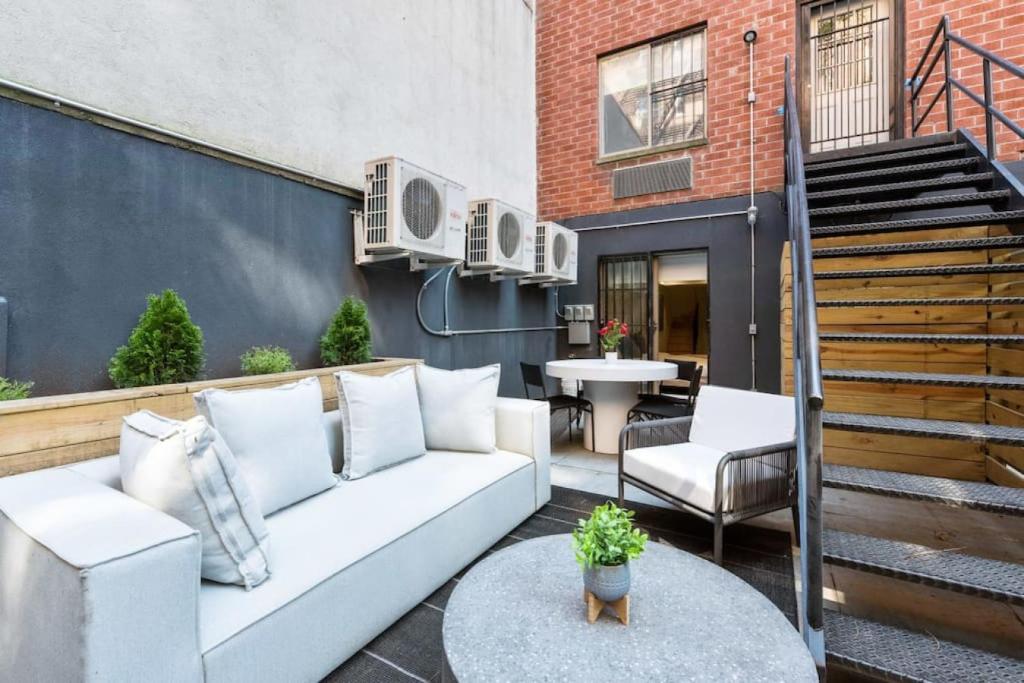 un patio con sofá, mesa y escaleras en Luxury 3BR Duplex w Private Patio in Upper East, en Nueva York