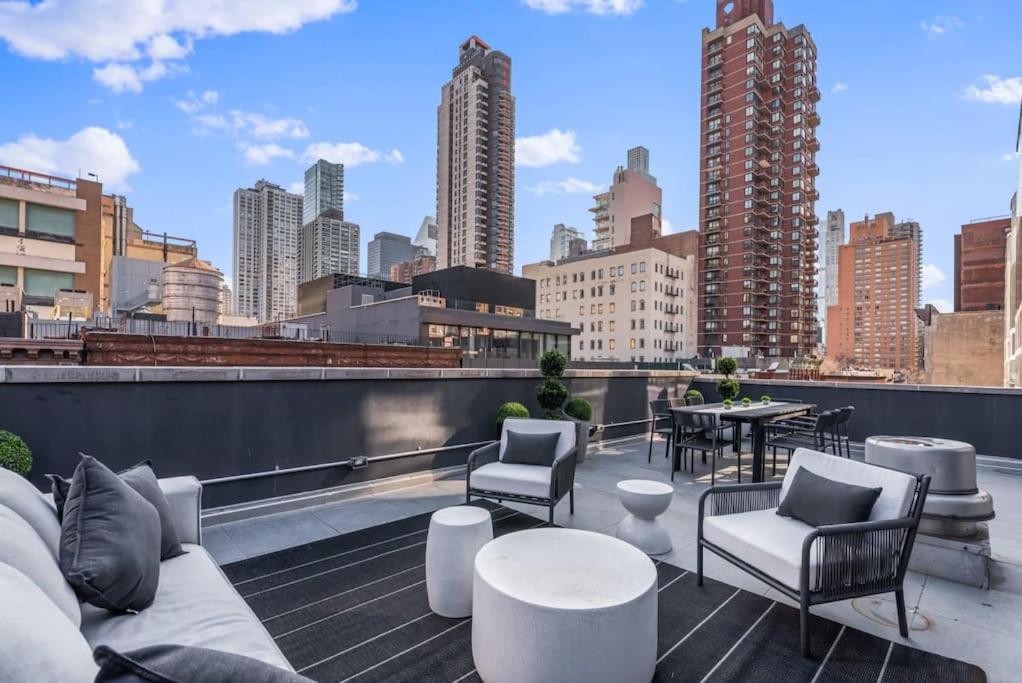 een dakterras met stoelen en tafels en een skyline van de stad bij 3BR Penthouse Suite with Massive Private Rooftop in New York