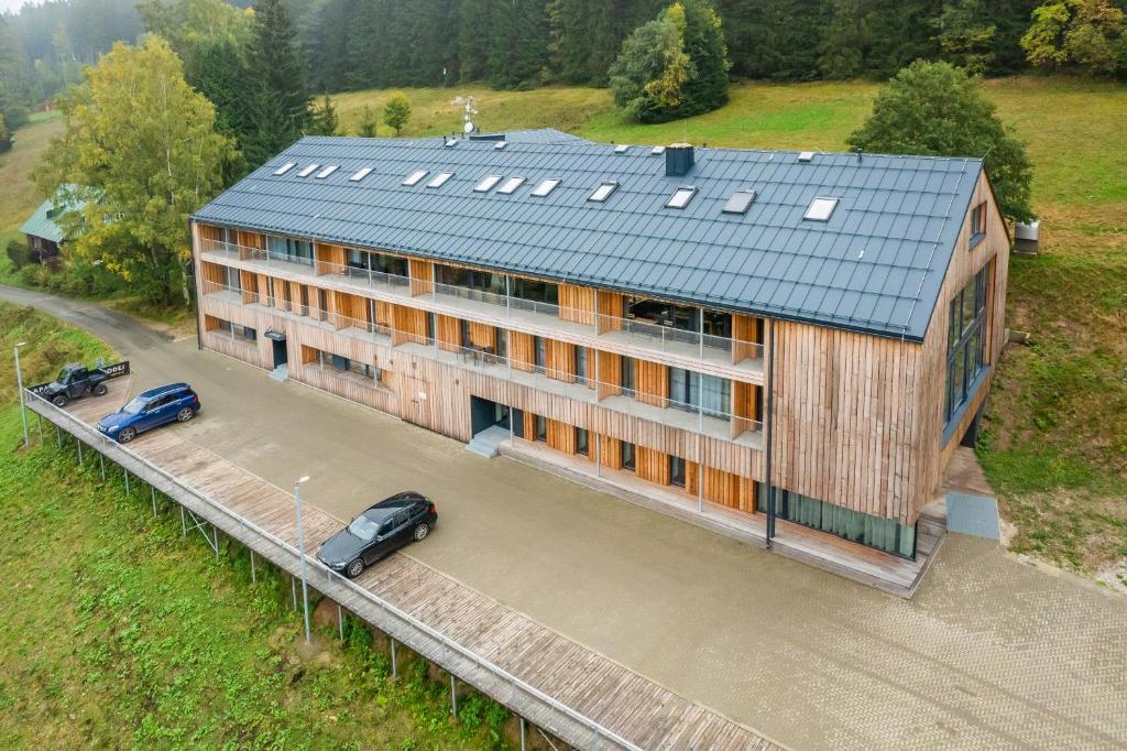 budynek z dwoma samochodami zaparkowanymi przed nim w obiekcie Rezidence Alpina w Szpindlerowym Młynie