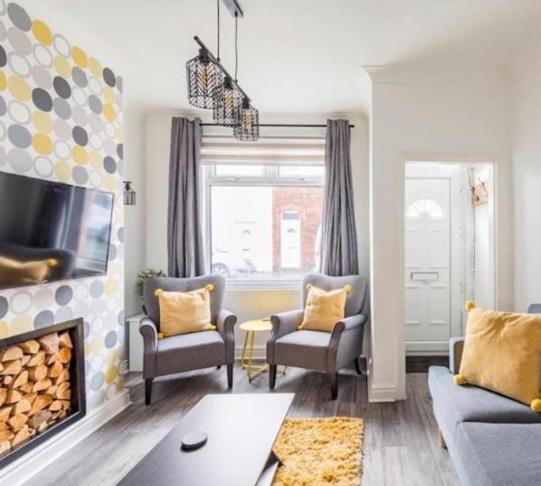 a living room with two chairs and a fireplace at Charming Terraced House in Central Hoylake in Hoylake