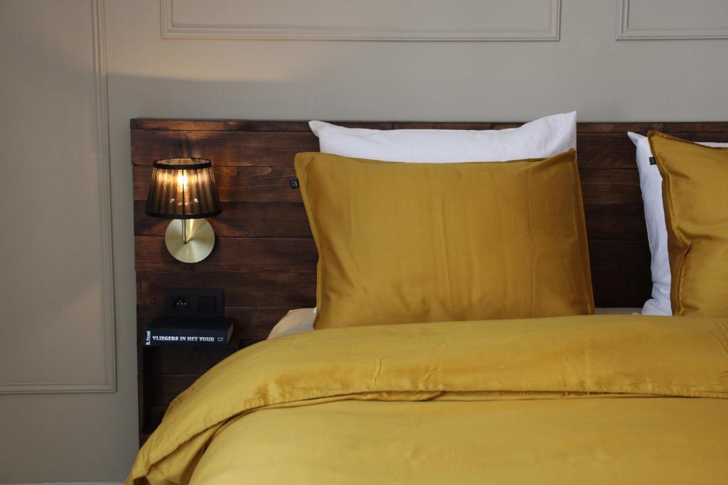 Un dormitorio con una cama amarilla con cabecero de madera. en Antwerp White House, en Amberes